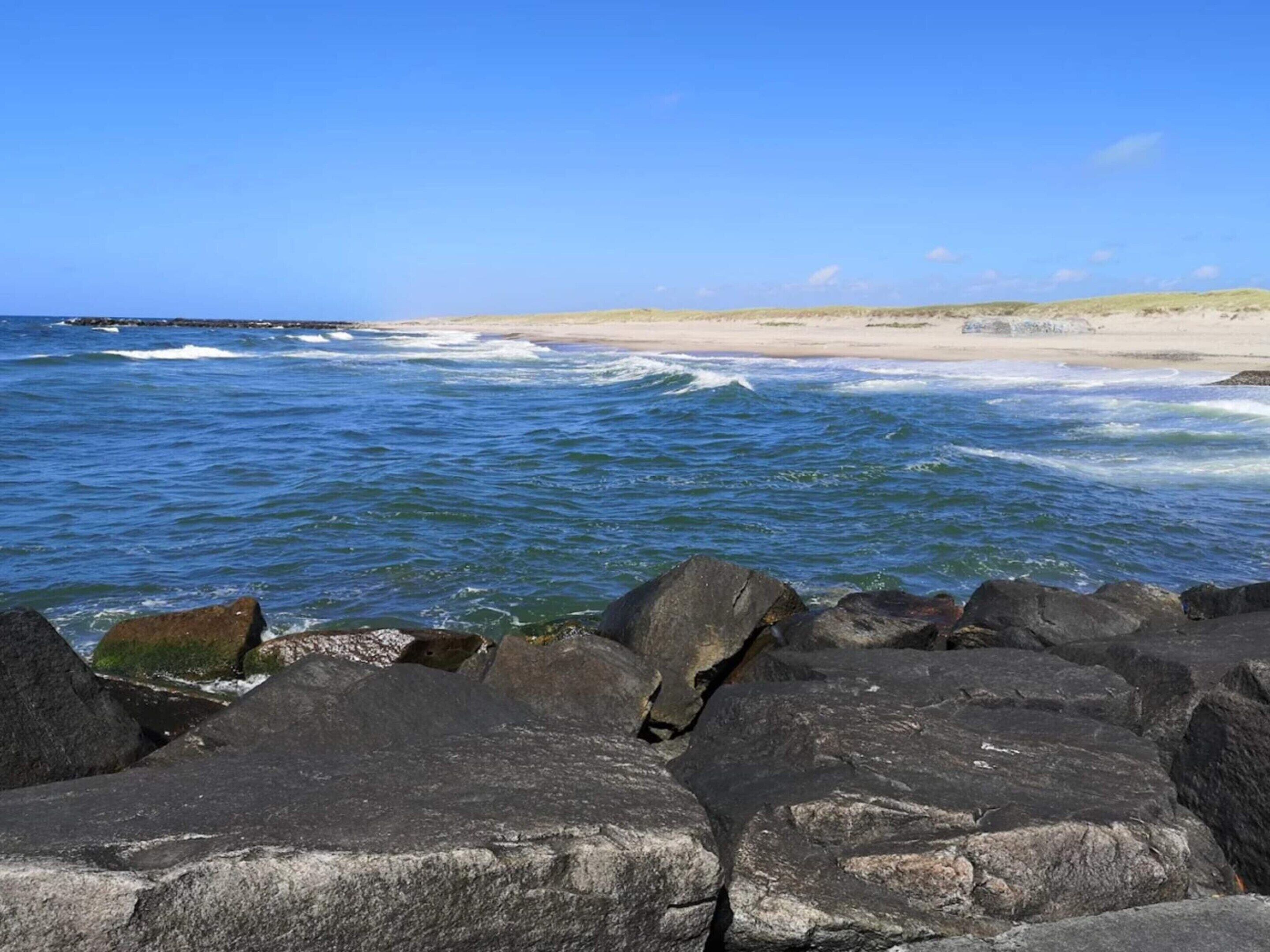 En stenig kustlinje där vågorna bryter mot stranden.