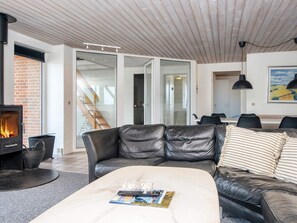 Un salon moderne avec une cheminée, des canapés en cuir, une table basse avec des magazines et un coin repas comprenant des chaises et une table.