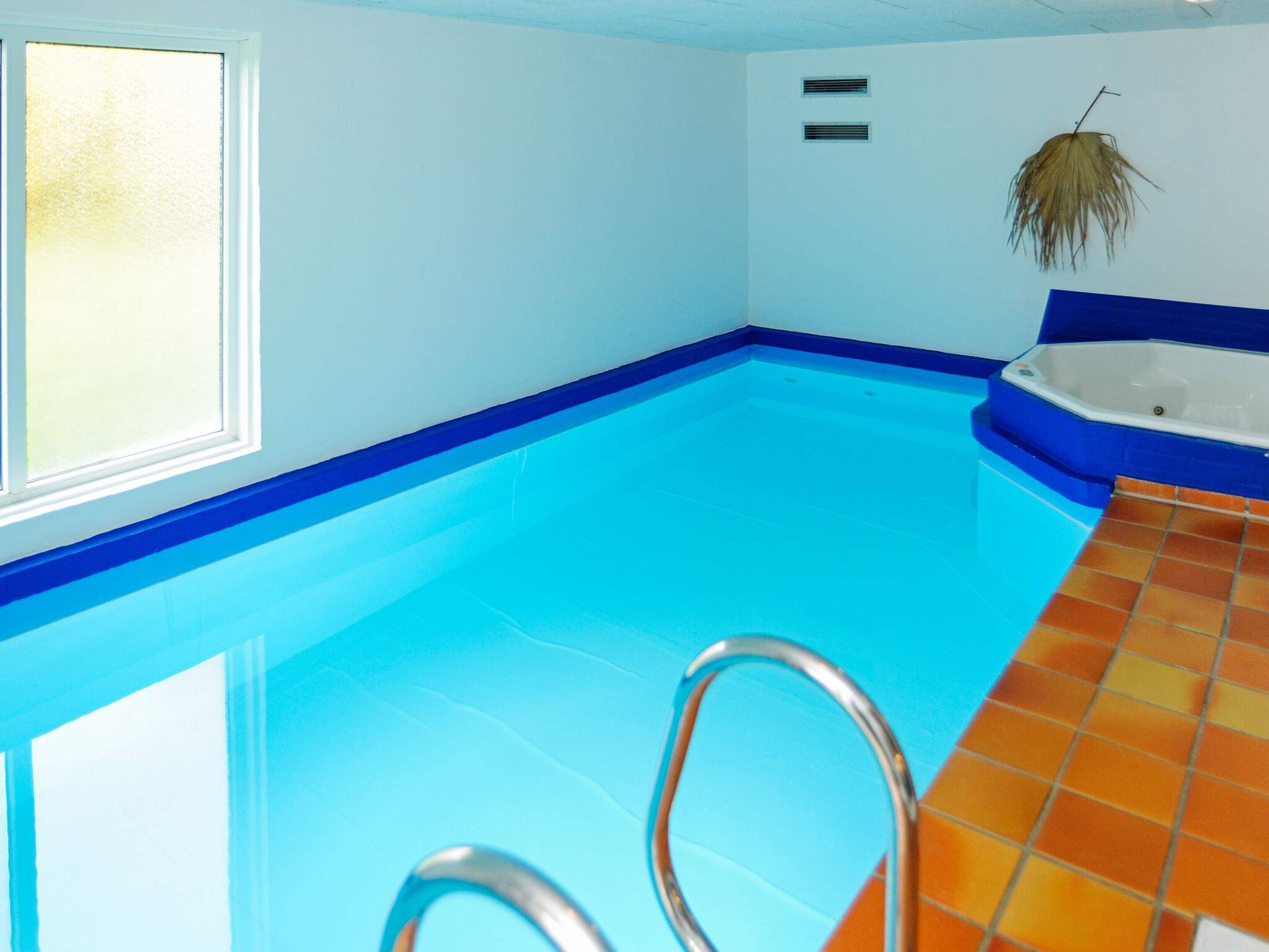 A swimming pool with a blue edge, a hot tub, and a window.