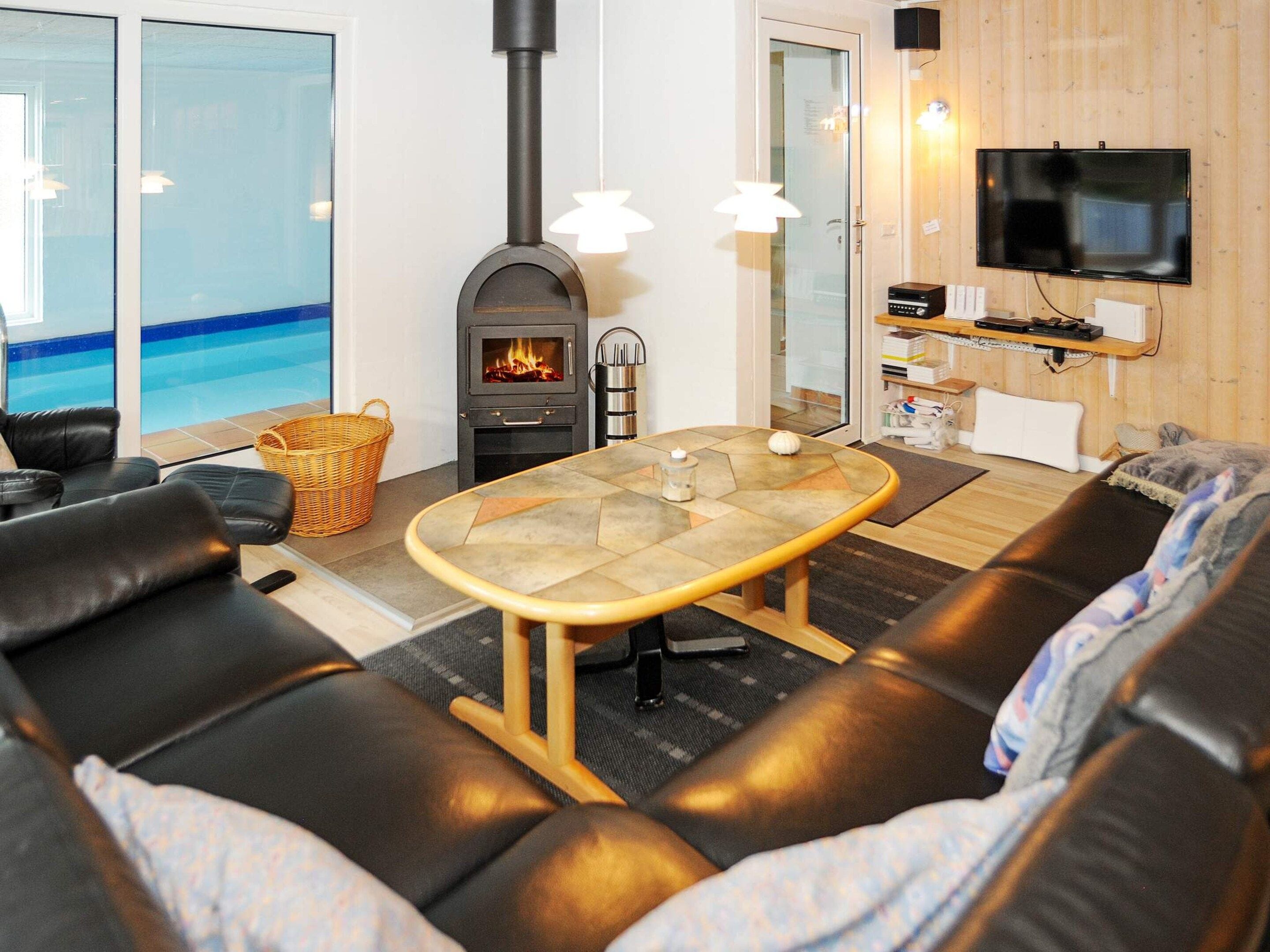 A cozy living room with a fireplace, a television, and a view of a pool.