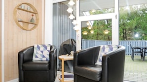 A room with two black leather chairs, a small round table, and a wicker wall decoration. - 4 Star Holiday Home in Norre Nebel (Norre Nebel)