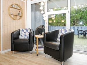 A room with two black leather chairs, a small round table, and a wicker wall decoration. - 4 Star Holiday Home in Norre Nebel (Norre Nebel)