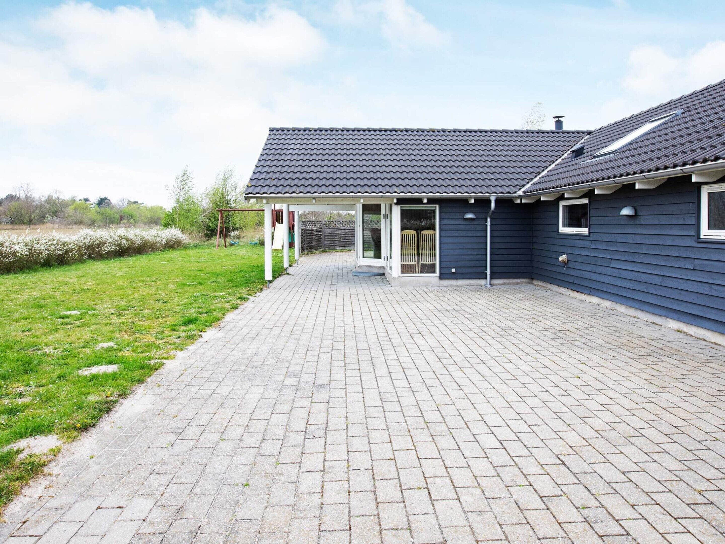 A house with a paved driveway leading to a covered patio area.