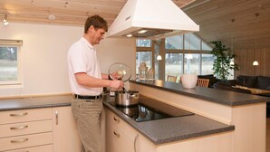 A modern kitchen with a large island, wooden cabinets, and a view of the outdoors.