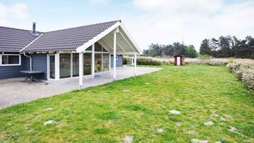 A house with a covered patio, a lawn, and a small shed.