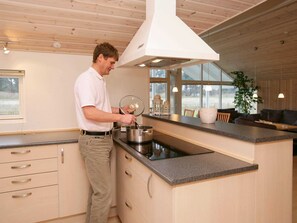 A modern kitchen with a central island, wooden cabinetry, and a large window providing natural light.
