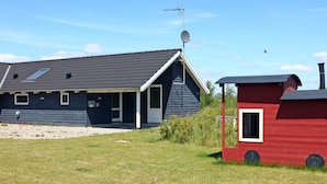 A house with a dark blue exterior, a satellite dish, and a red outbuilding.