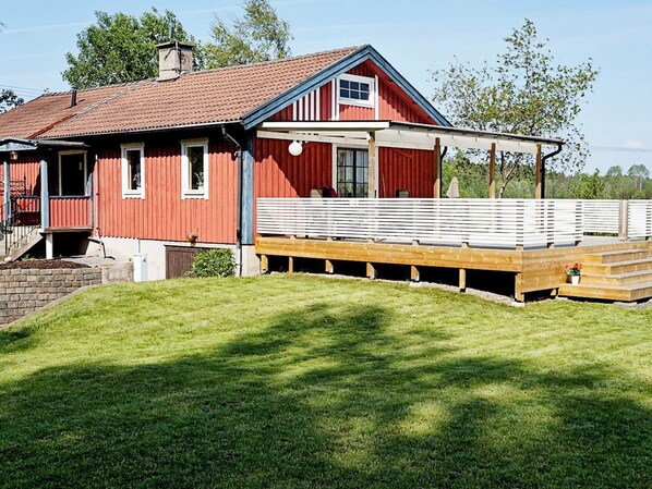 A red barn with a wooden deck and a covered porch.