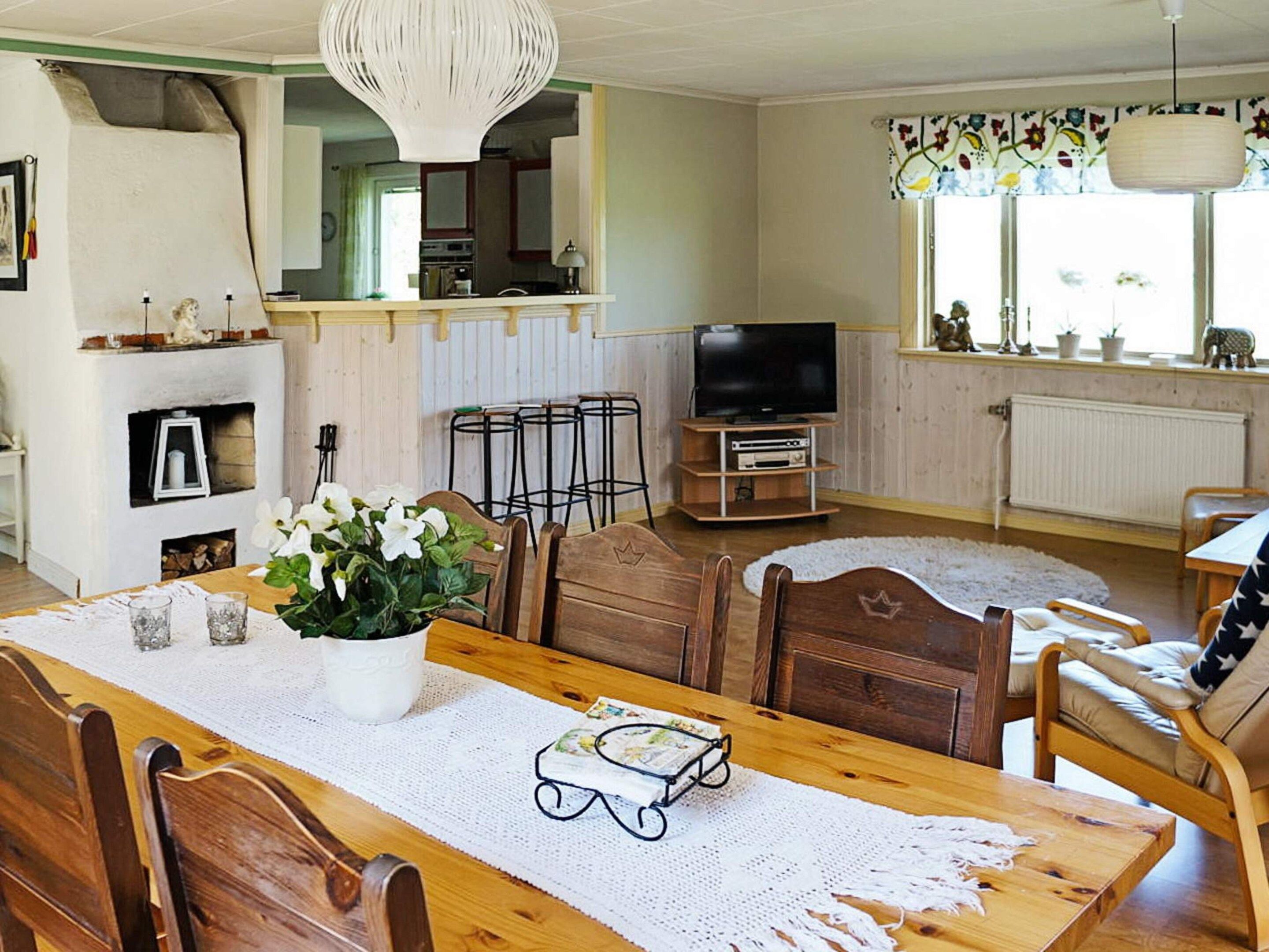 A cozy living room with a wooden dining table, chairs, a television, and a fireplace.