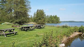Un área de picnic junto al lago con mesas y una masa de agua tranquila.