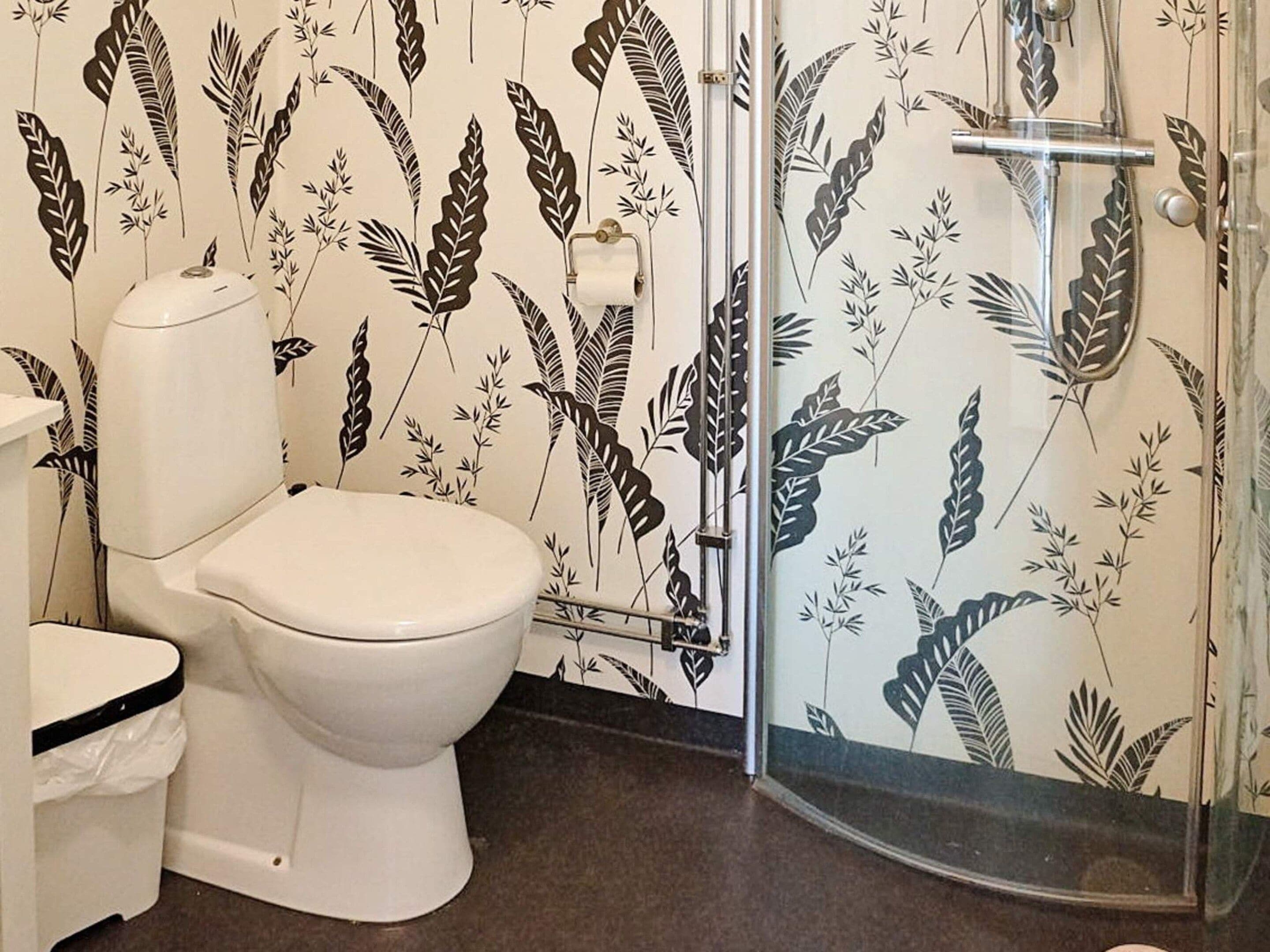 Ein Badezimmer mit Toilette, Duschkabine und Toilettenpapierhalter.