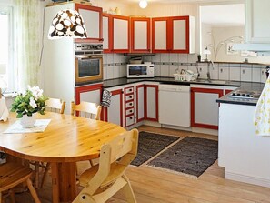 A kitchen with red and white cabinets, a wooden dining table, and a microwave.