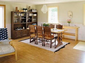 A dining area with a wooden table and chairs, a bookshelf, and a window with natural light.