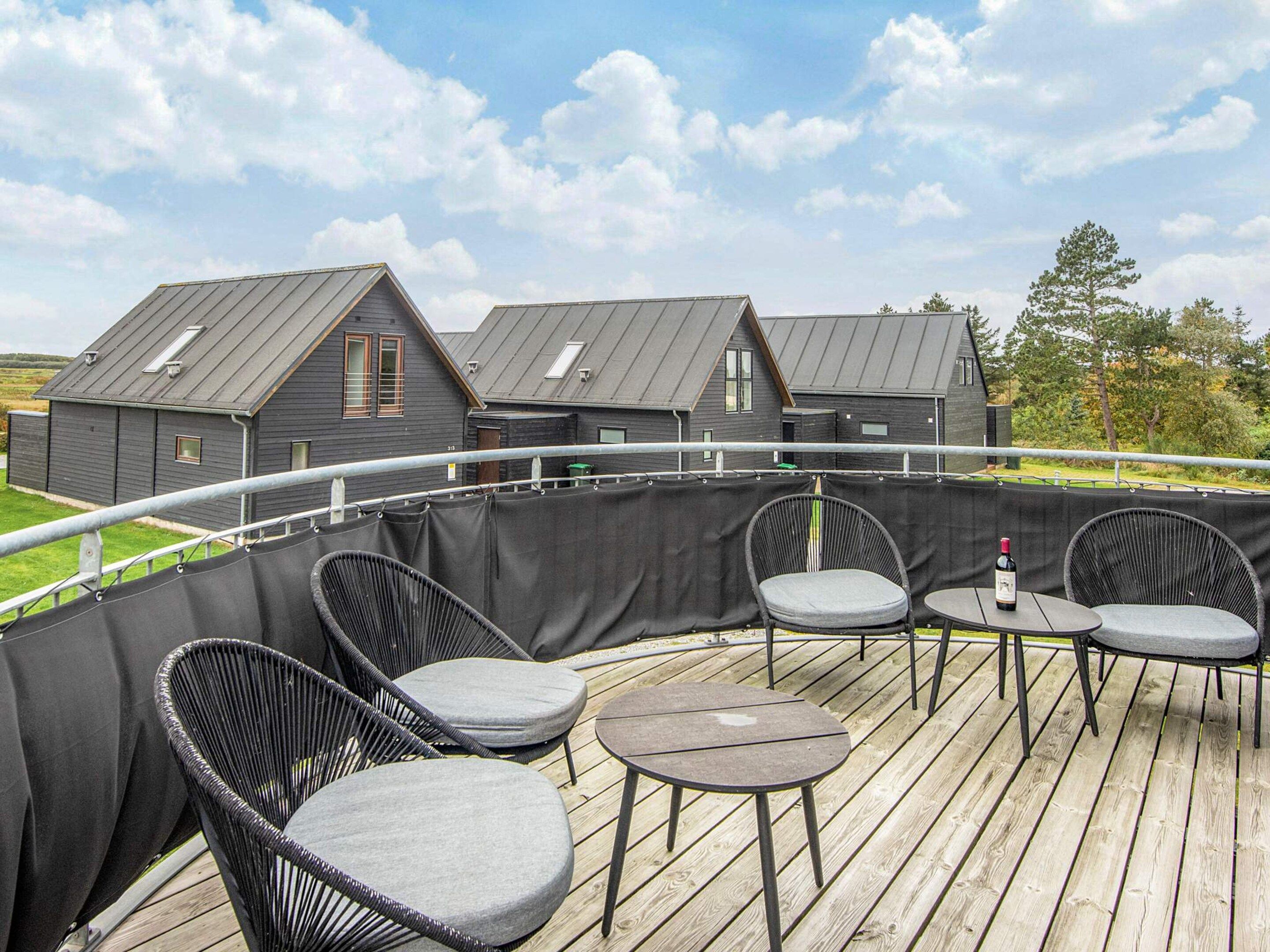 A wooden deck with outdoor seating and a view of residential buildings in the background.