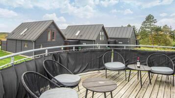 A wooden deck with outdoor seating and a view of residential buildings in the background.