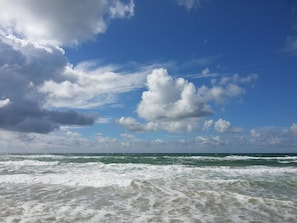 A beach with waves and a partly cloudy sky.