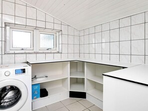 Une buanderie équipée d’un lave-linge, d’étagères et d’une fenêtre.
