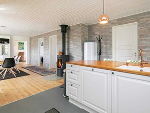 A modern kitchen with a central stove, white cabinetry, and a wooden countertop.