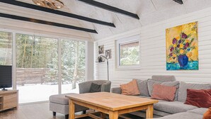 A modern living room with a wooden coffee table, grey sofas, and a large window offering a view of a snowy landscape. - 4 Star Holiday Home in Blavand (Blavand)
