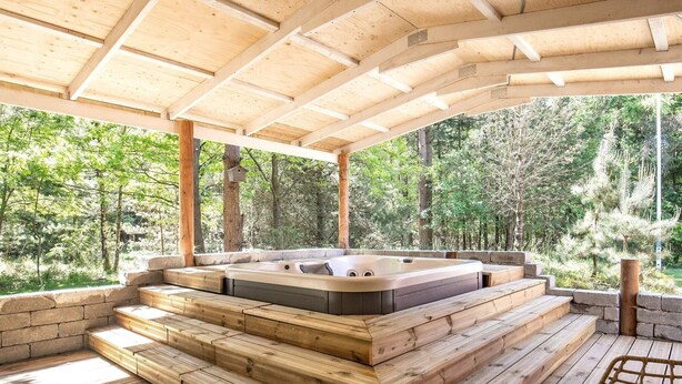 A hot tub area with wooden steps and a view of the forest. - 4 Star Holiday Home in Blavand (Blavand)