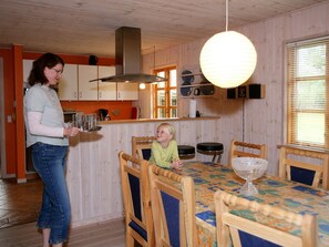 A wooden interior with a dining table, chairs, and a kitchen area.