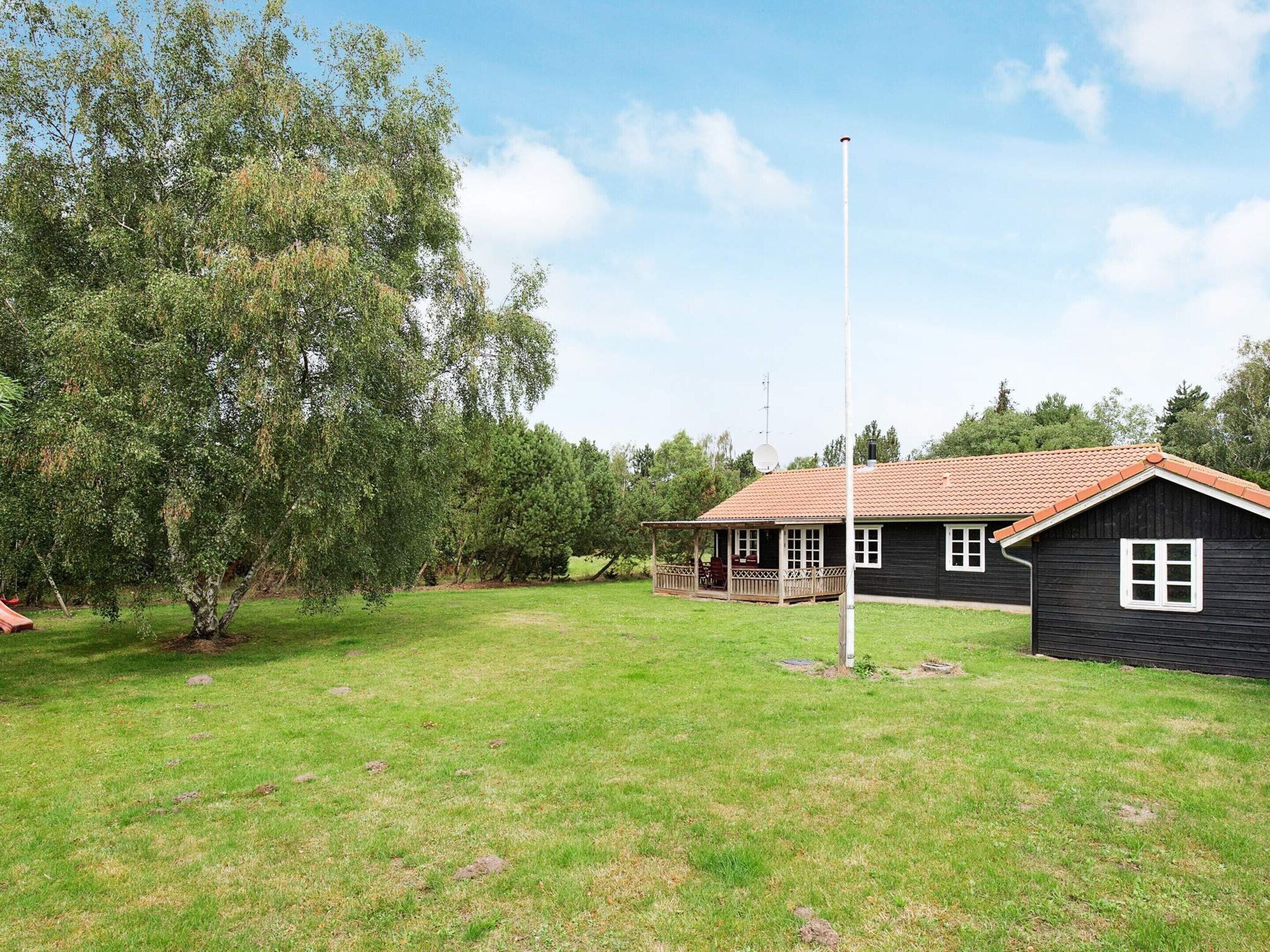 A house with a porch, a flagpole, and a grassy yard.