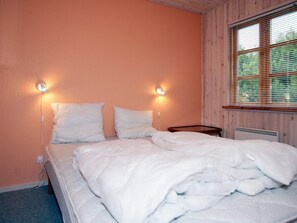 A single bed with two bedside lamps, a wooden headboard, and a window with blinds.