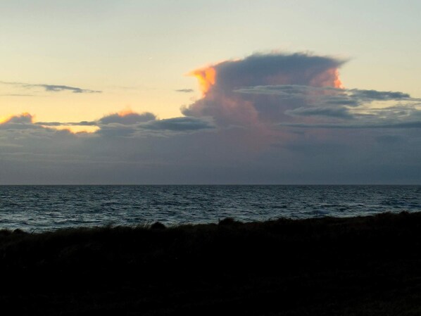 A coastal scene with a body of water and a cloudy sky.