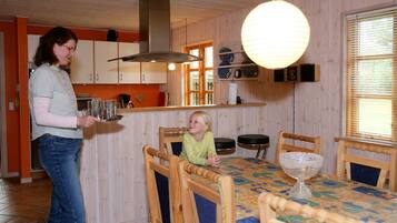 A wooden interior with a dining table, chairs, and a kitchen area.