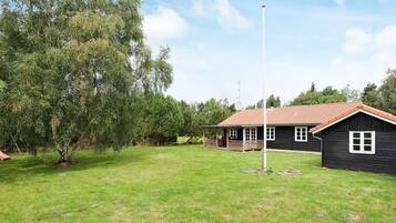 A house with a porch, a flagpole, and a grassy yard.