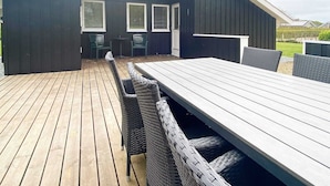 An outdoor patio with a wooden deck, a long table, and wicker chairs. - 4 Star Holiday Home in Hemmet (Hemmet)