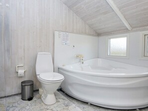 A bathroom with a white toilet, a white bathtub, and a marble floor. - 4 Star Holiday Home in Hemmet (Hemmet)