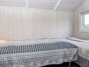 Une pièce avec un lit, une fenêtre et des murs en bois.