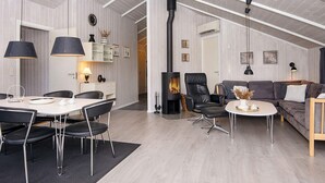 A modern living room with a high ceiling, a fireplace, a dining area with a table and chairs, and a seating area with a sofa and armchairs. - 4 Star Holiday Home in Hemmet (Hemmet)
