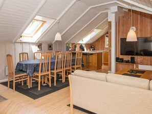 A cozy loft-style room with a dining area, kitchenette, and a TV.