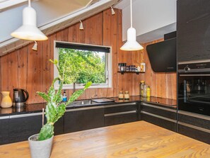 A modern kitchen with wooden walls, a window, and a built-in oven.