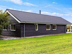 Un bâtiment long et étroit, à l’extérieur sombre, doté d’un toit en pente et de nombreuses fenêtres.