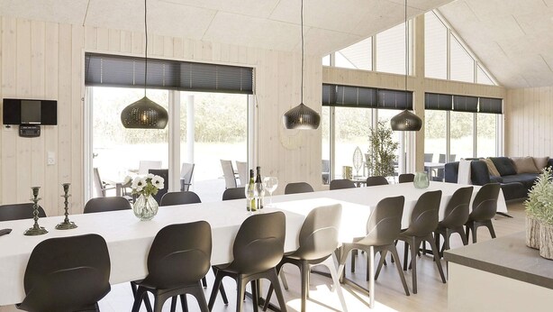 A spacious dining area with a long table, multiple chairs, pendant lighting, and large windows. - 5 Star Holiday Home in Idestrup (Idestrup)