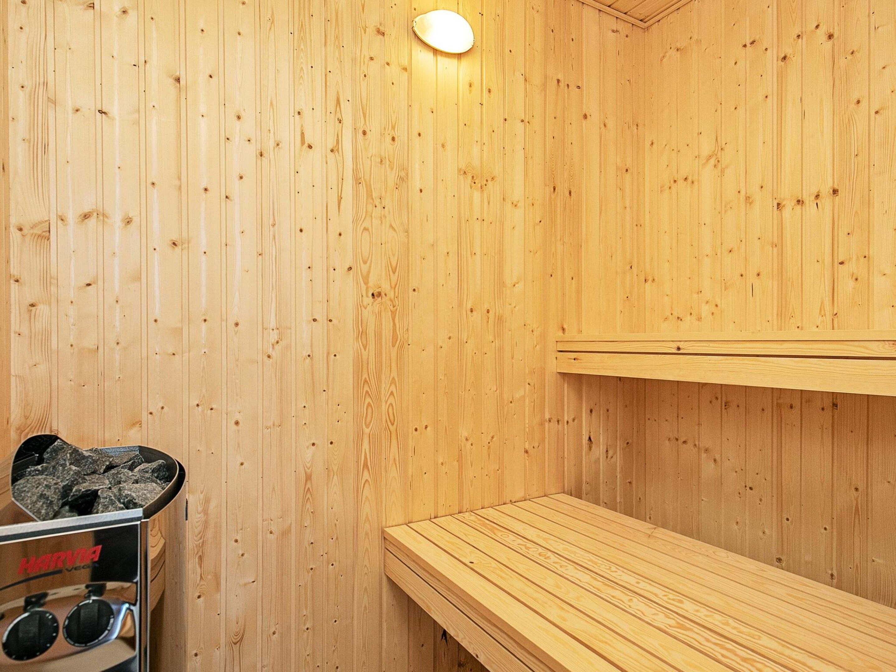 A sauna with wooden walls, a bench, and a sauna heater.