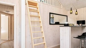 A kitchen with wooden paneling, a wooden ladder, a mirror, pendant lights, and a bar stool. - 5 Star Holiday Home in Idestrup (Idestrup)
