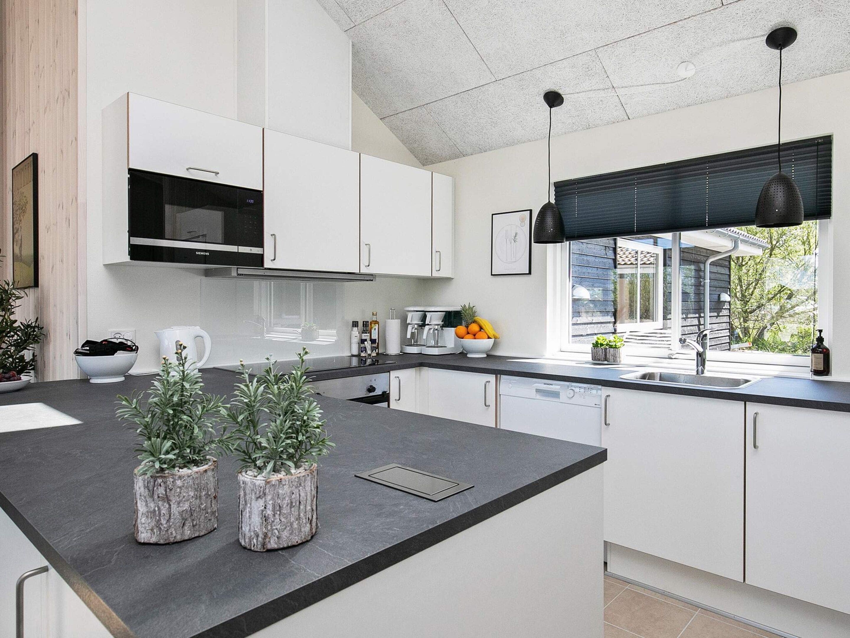 A modern kitchen with white cabinets, a black countertop, and a window with a view of the outdoors.