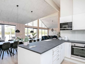 Een moderne keuken met een groot schiereiland, witte kastjes en een Siemens oven.