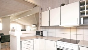 A modern kitchen with white cabinets, a microwave, and an oven.