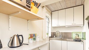 Une cuisine avec des meubles blancs, une bouilloire en acier inoxydable, un évier et une cuisinière de style rétro.