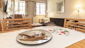 Un salon chaleureux avec une table en bois, un canapé et une table à manger agrémentée d’une assiette décorative.