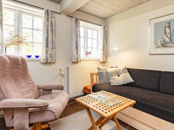 Relax in a comfortable seating area with a plush armchair and sofa, accompanied by a small table and artwork.