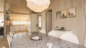A modern kitchen with wooden cabinets, a dining table with a geometric pattern, and a pendant light. - 4 Star Holiday Home in Blokhus (Blokhus)