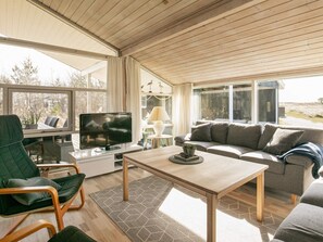 A spacious living area with a television, sofa, and dining table.