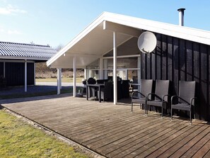 A covered outdoor area with a wooden deck, outdoor furniture, and a satellite dish.