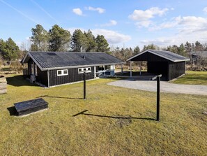 A rustic cabin with a metal roof, a covered outdoor seating area, and a gravel path leading to a wooden deck.